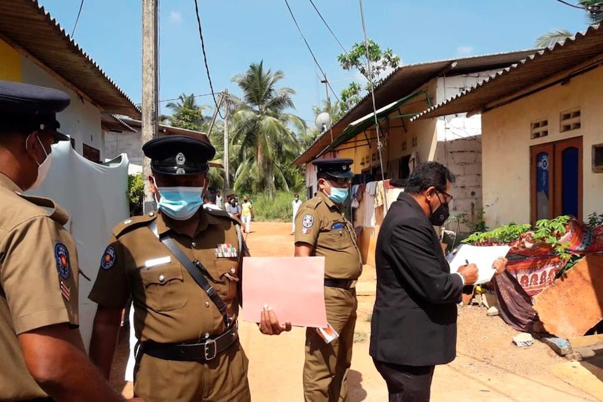 Sri Lankan magistrate Wasantha Ramanayake and police officers inspect outside a house.
