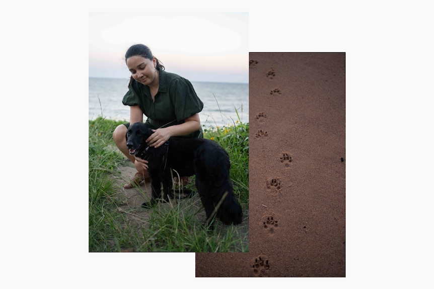 Dr Anna Sri smiles while petting a black dog in front of a coastal backdrop
