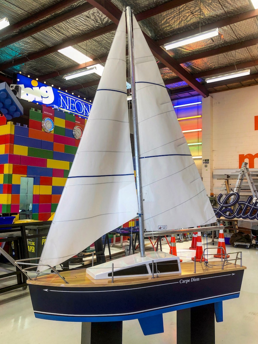 A coffin in the shape of a sailing boat. It has tall sails and a rudder.