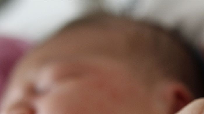 A mother holds her baby's hand in hospital