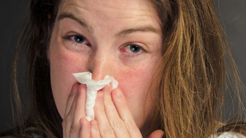 Woman with flu blowing her nose