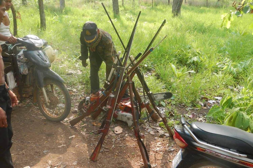 About a dozen guns and chainsaws confiscated on a patrol of Phnom Tnout forest piled in a tepee shape.