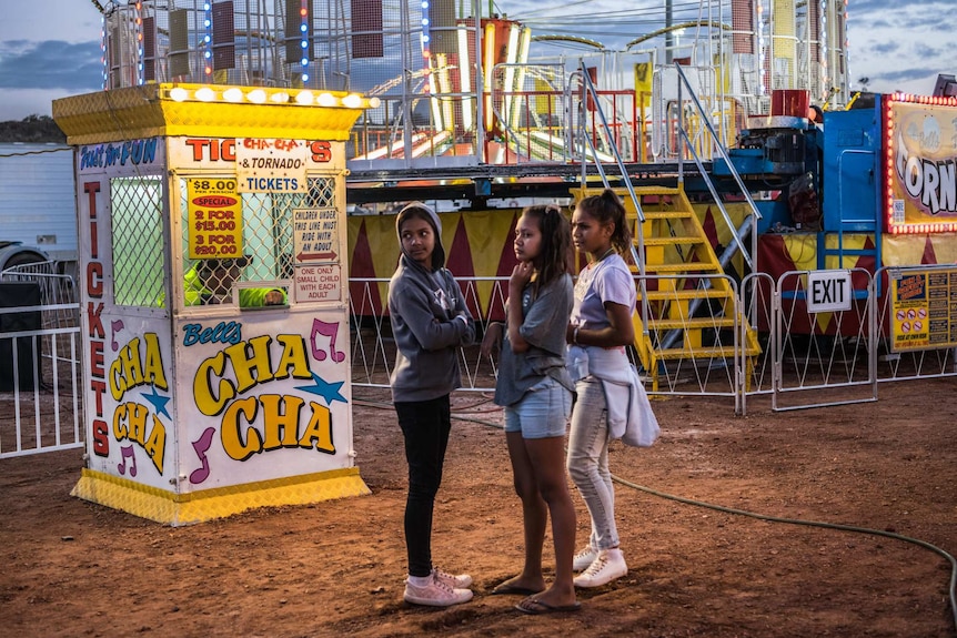 Three girls are pictured among rides.