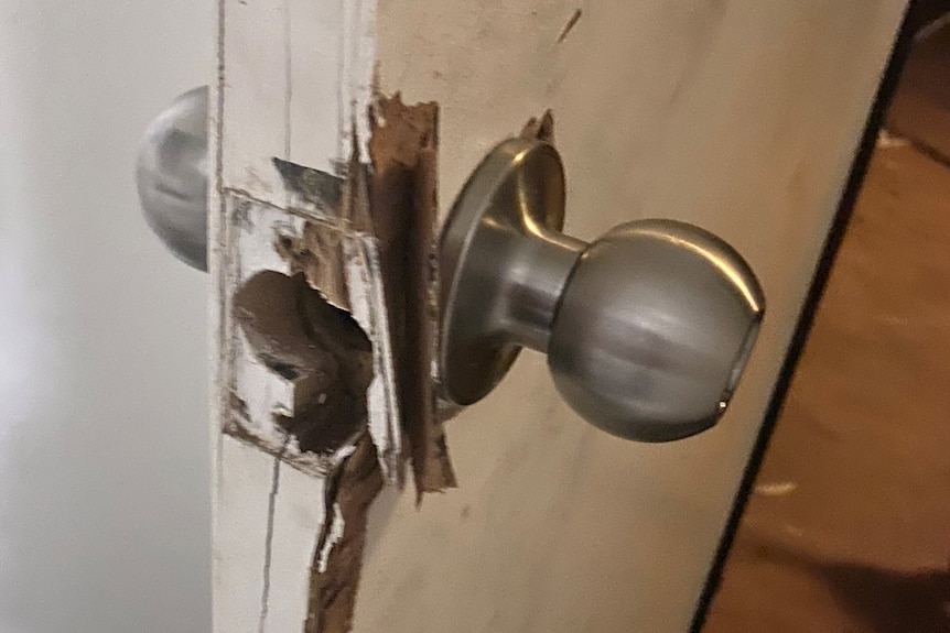 A busted door handle on a wooden door