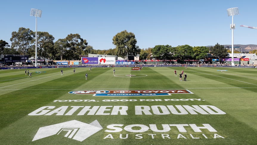 A picture taken looking across an AFL ground with the words "Gather Round South Australia" painted on the grass.