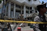 A policeman inspects the cordoned-off site of a bomb blast in Bangkok