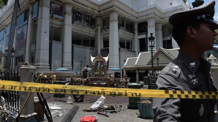 A policeman inspects the cordoned-off site of a bomb blast in Bangkok