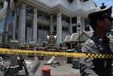 A policeman inspects the cordoned-off site of a bomb blast in Bangkok