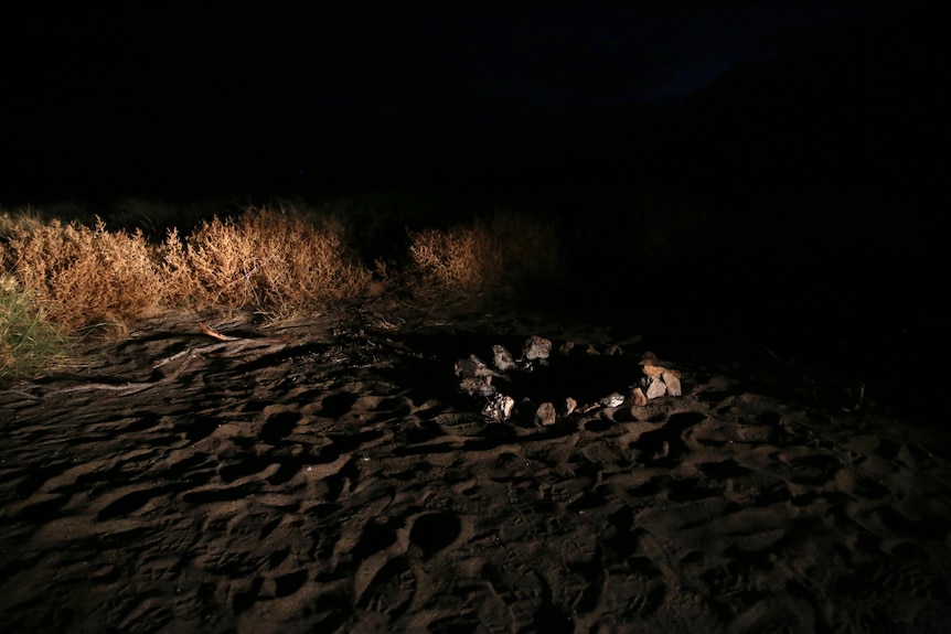 A fire place in the sand at night