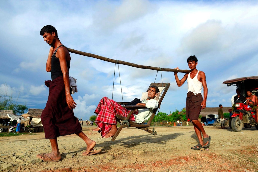 Rohingya men carry a patient to a hospital outside Sittwe.