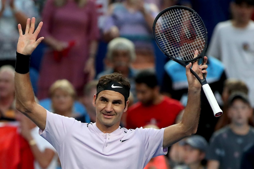 Roger Federer raises his arms in triumph after beating Jack Sock at the Hopman Cup.