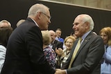 Scott Morrison smiles as he shakes hands with a smiling John Howard.