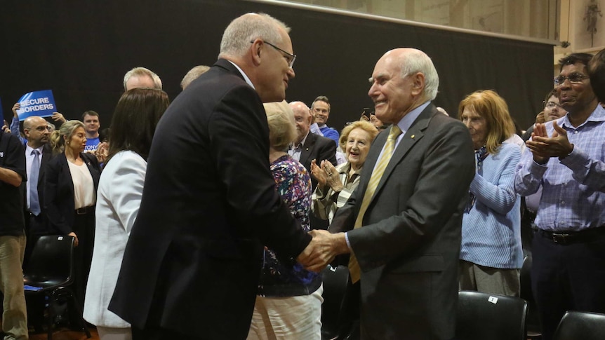 Scott Morrison smiles as he shakes hands with a smiling John Howard.