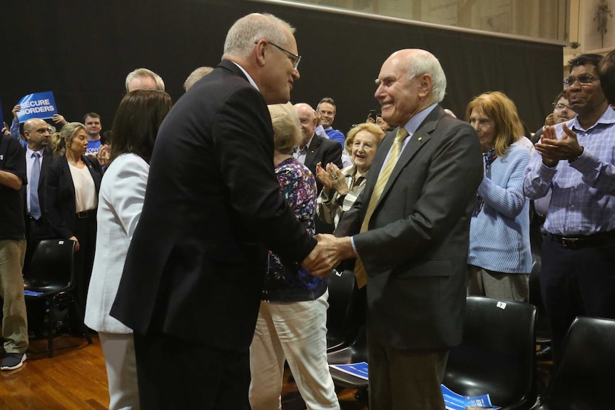 Scott Morrison smiles as he shakes hands with a smiling John Howard.