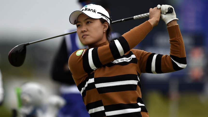 Minjee Lee holds a pose with her club behind her head after playing a shot wearing a stripy jumper