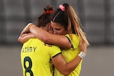 Two Australian female rugby sevens players embrace as they console each other after losing to Fiji.