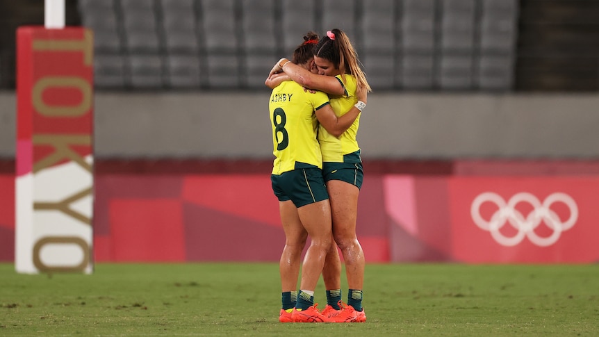 Two Australian female rugby sevens players embrace as they console each other after losing to Fiji.