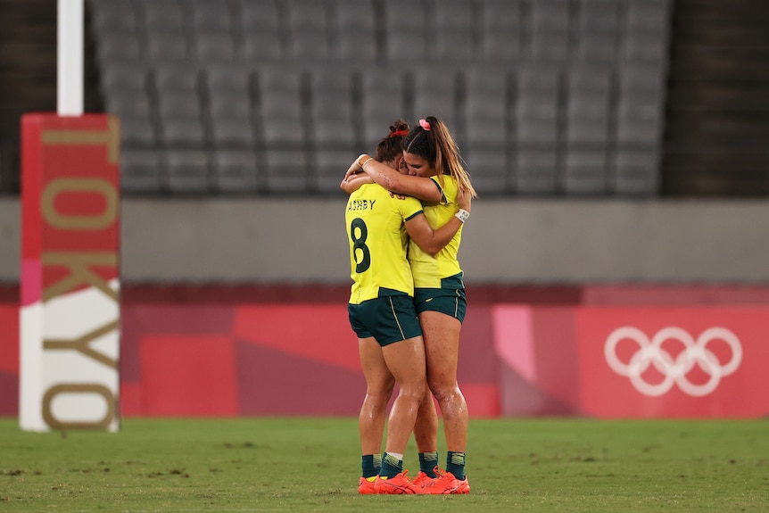 Two Australian female rugby sevens players embrace as they console each other after losing to Fiji.