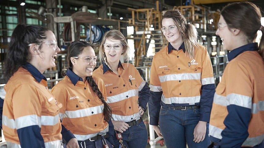 Group of smiling young women in high vis, hi-vis, no hard hats at Aurizon rail freight yard