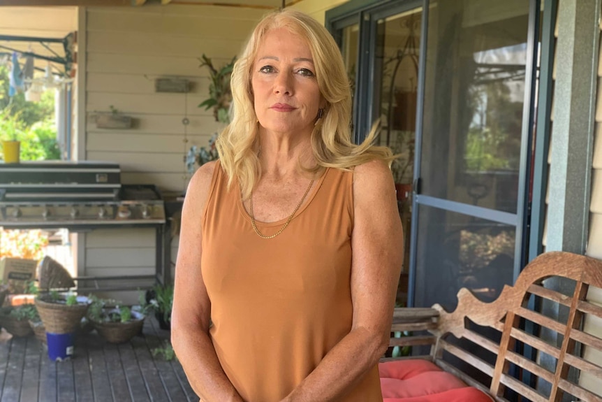 Karen Egan stands on a verandah with her hands clasped in front of her.