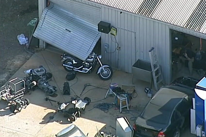 A number of items outside a shed on the property including a motorcycle.