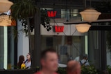 People walk past Westpac branch with red signage in Brisbane CBD