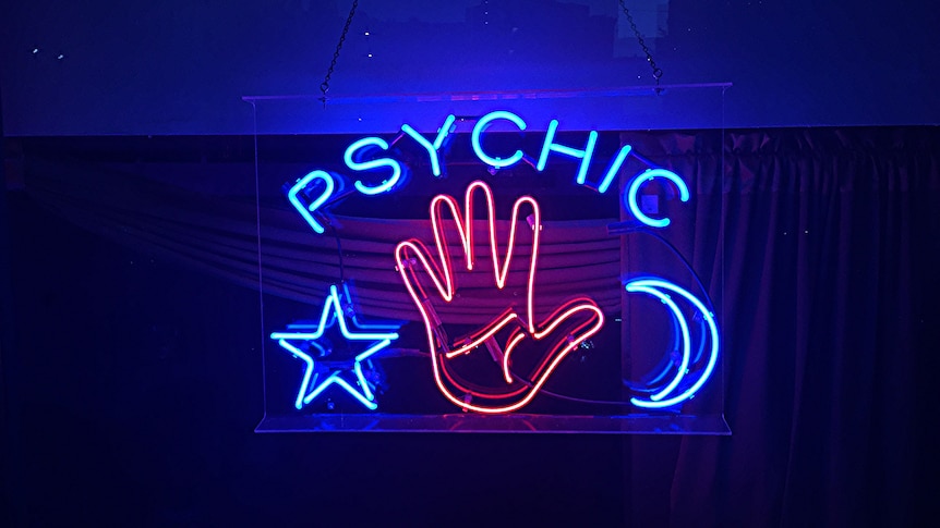 A blue and red neon sign spells 'psychic' above a lit up star, moon and hand