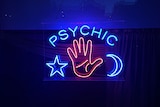 A blue and red neon sign spells 'psychic' above a lit up star, moon and hand