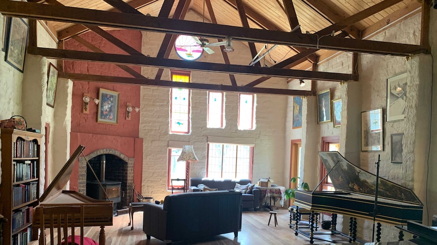 Light streams into a high ceilinged mudbrick house, with neatly arranged furniture inside and a harpsichord.