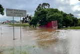truck in floodwater next to a road subject to flooding sign.