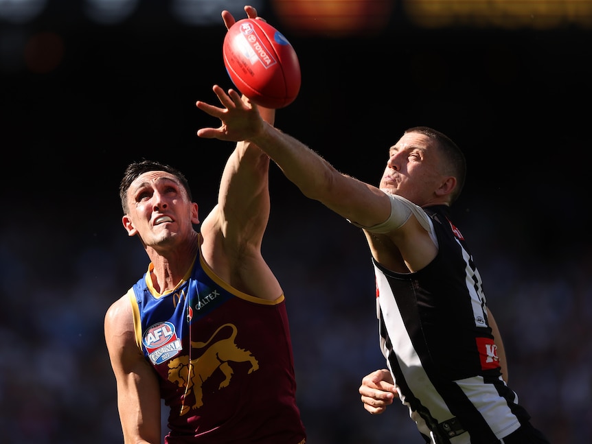 A Collingwood and Brisbane opponent contest for the ball in the AFL grand final.