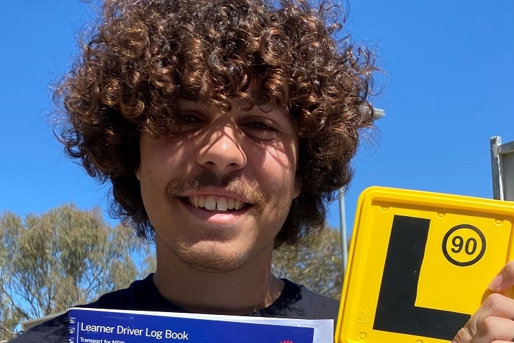 Young indigenous man holding up a P plate