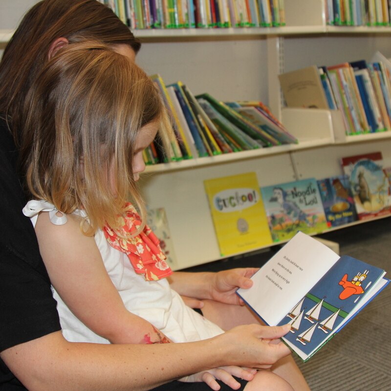 A mother reads to her daughter at the library