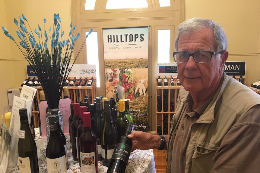 Hilltops Inc president Peter Creyke holding a bottle of wine in the regional wine centre at Young, NSW.