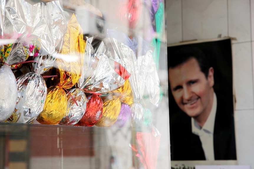 Coloured eggs are displayed in a shop front near a picture of Syria's President Bashar al-Assad