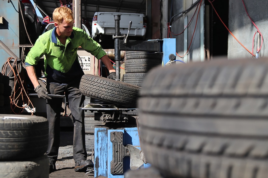 A fitter removes a tyre from a wheel rim at a recycling yard