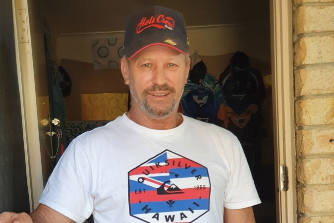 A man smiles as he stands at the front door to a home.