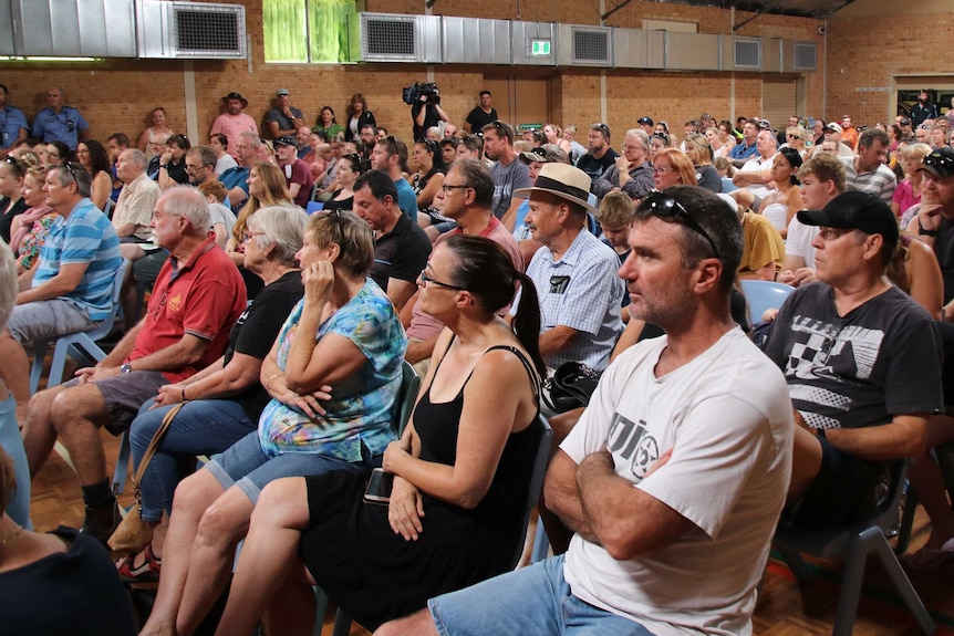 A group of people sit in a community hall.