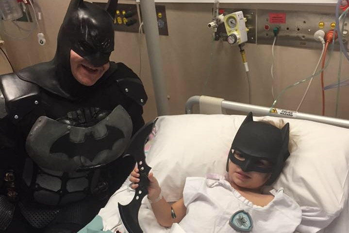 Eamon Obst in a hospital bed getting a visit from Batman.