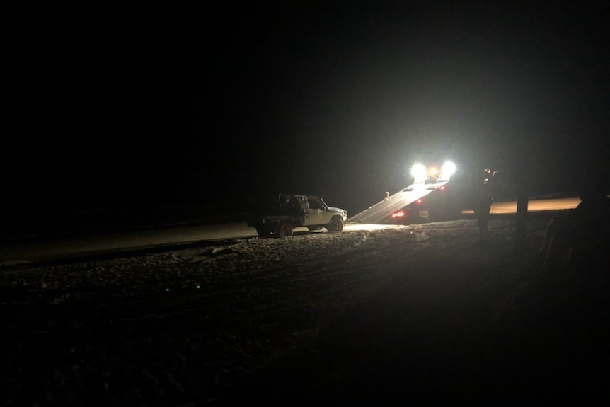 A tow truck taking away the car involved in a rollover on Teewah Beach on Saturday that put two teenagers in hospital.