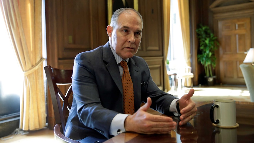 EPA administrator Scott Pruitt sits at a desk gesturing with his hands.