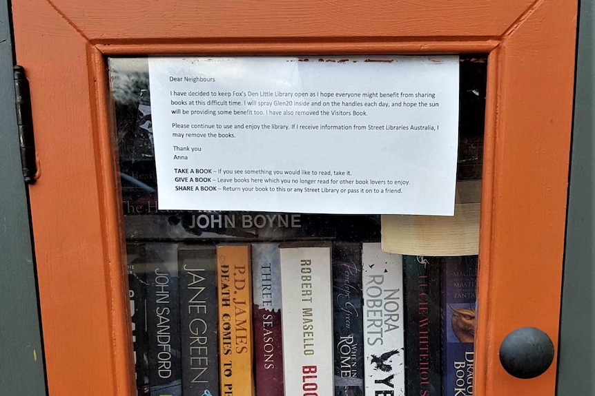 A stack of books sit inside a glass cabinet on the street.