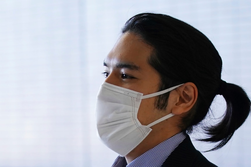 Kei Komuro wearing a mask and sporting a pony tale hairstyle. 