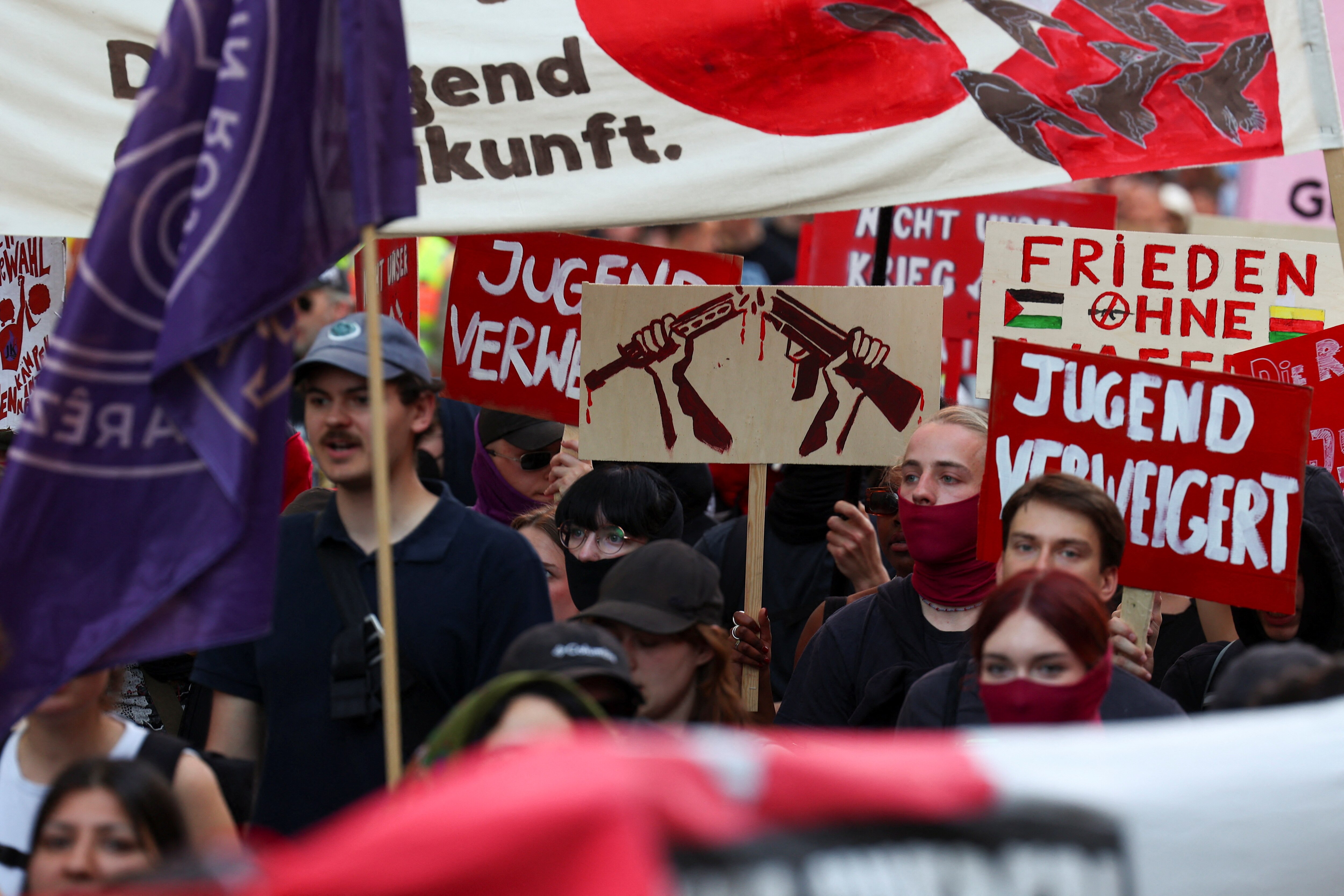 Protests hold up signs, with the most visible one of a gun torn in half 