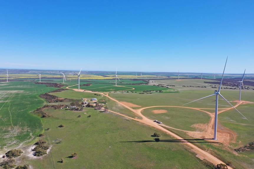 Aerial shot of huge three-bladed wind turbines in a flat landscape of paddocks