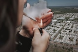 a woman smoking a cigarette over an aerial image of dwellings
