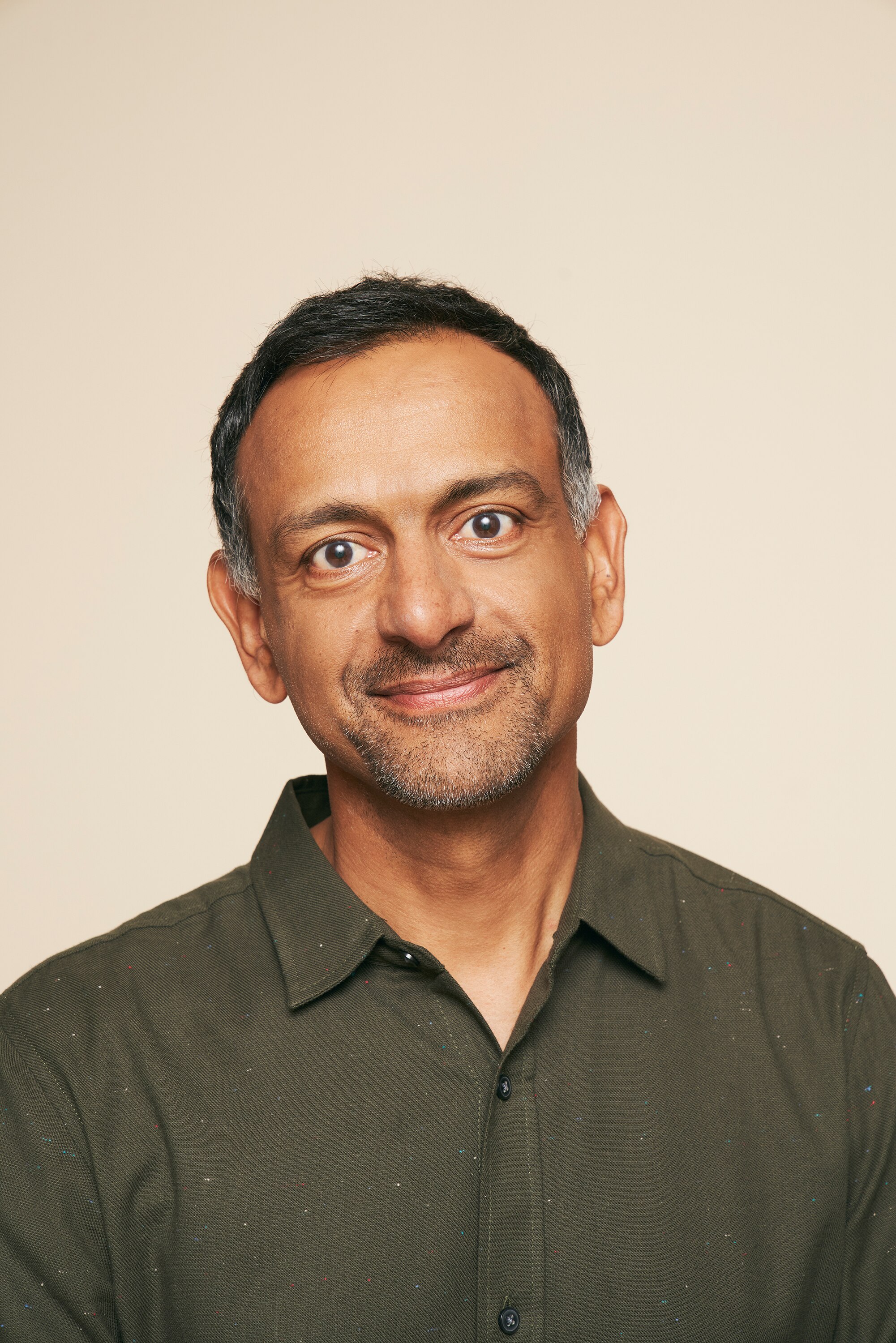 一个穿着绿领衬衫、面带微笑的男人。