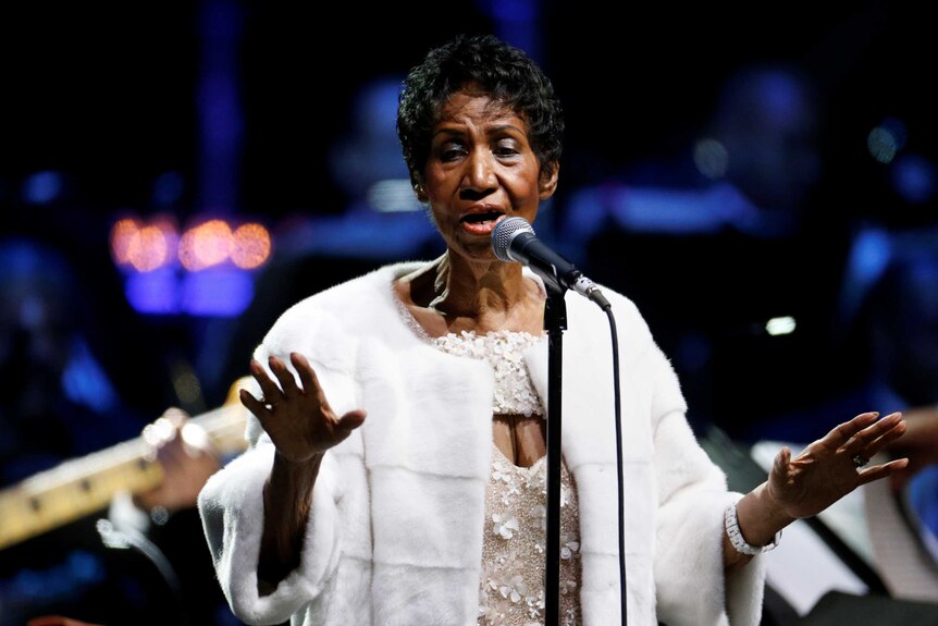 Aretha Franklin performs a song dressed in white 