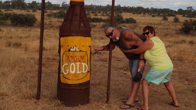 Steve and Debi Murphy pose by a beer bottle statue.