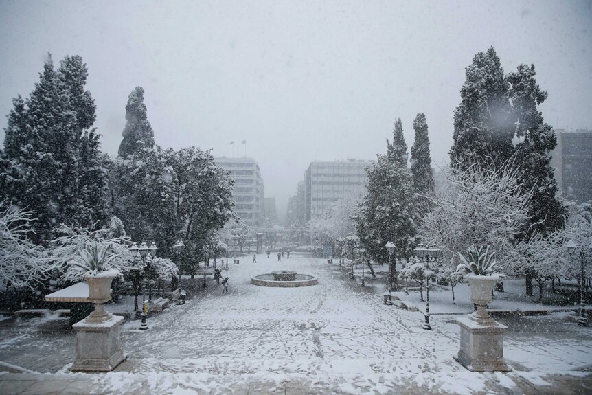 Pedestrians walk at the snow covered Syntagma square.